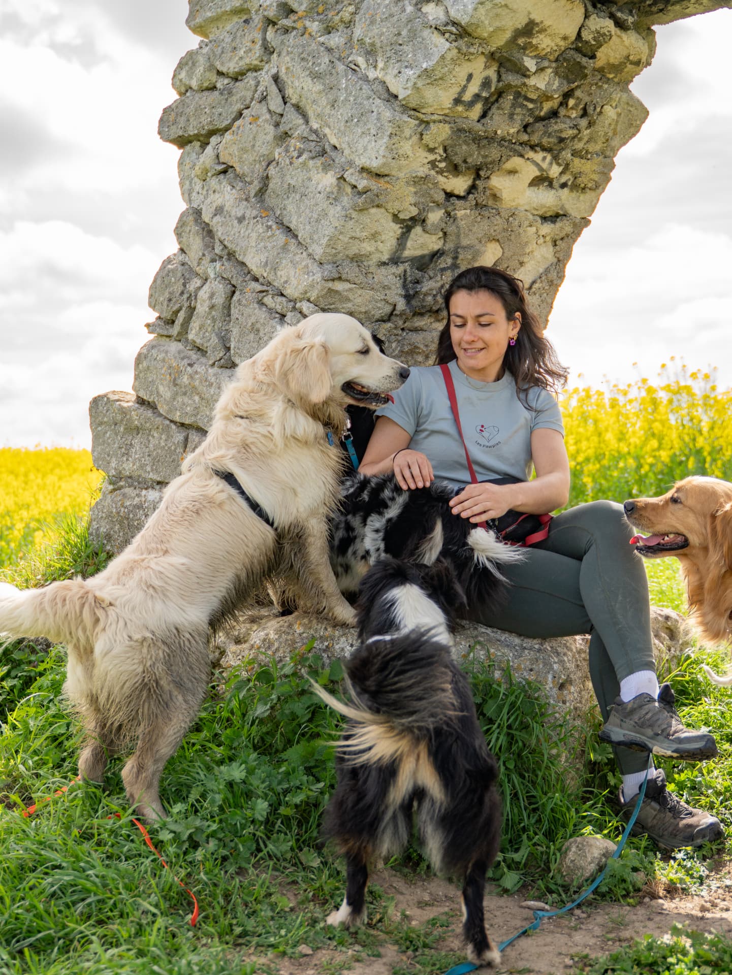 Léna entourée de chiens au pied d'une pierre ancienne